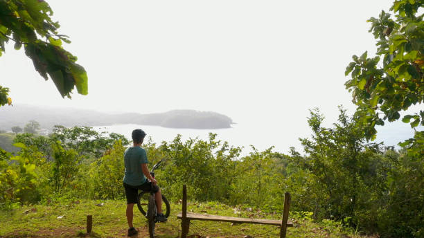 istock Mountain biker rides above tropical rainforest in the morning 1296724126