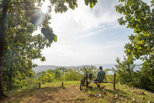 Mountain biker relaxes above tropical rainforest in the morning