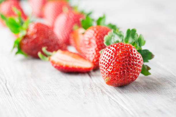 istock Juicy fresh strawberries on old white wooden background. 1296725529