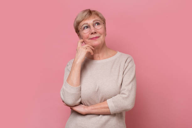 istock Thinking senior woman in front of colored background 1296727556