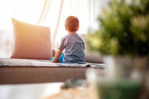 Boy from back, looking trough the window. Boy from back, looking trough the window. Little boy sitting on sofa at home. Child autism. Depressed little boy sitting on the sofa. Unhappy child  Alone at home. Upset. autism photos stock pictures, royalty-free photos & images