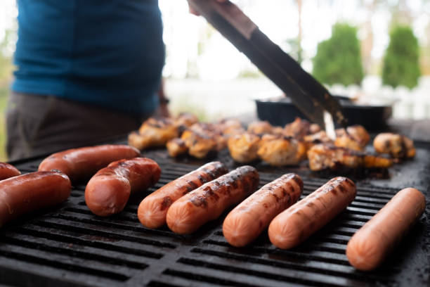 istock Sausages grilling outdoors on a gas barbecue grill. 1296728879