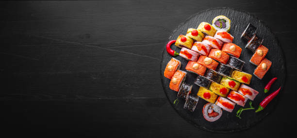 set of sushi roll with salmon, avocado, cream cheese, cucumber, rice, tuna in plate on black background