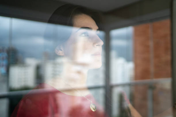 istock Young woman looking through window 1296729930
