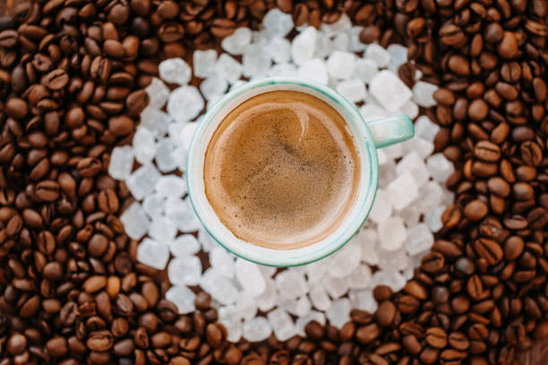 nahaufnahme eines leckeren espresso-kaffee in der mitte eines kreises von weißen süßigkeiten und gerösteten kaffeebohnen wie ein mandala direkt von oben - comfort food high angle view directly above close up stock-fotos und bilder
