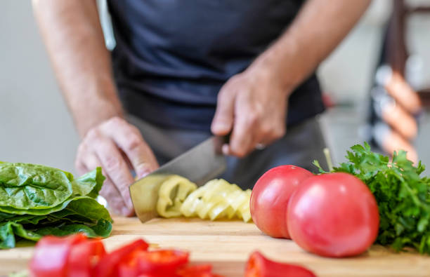 istock Close up of man's hands while chopping fresh vegetables on cutting board 1296734326