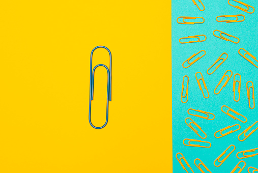 Big paperclip and standard paperclips on the two color background.