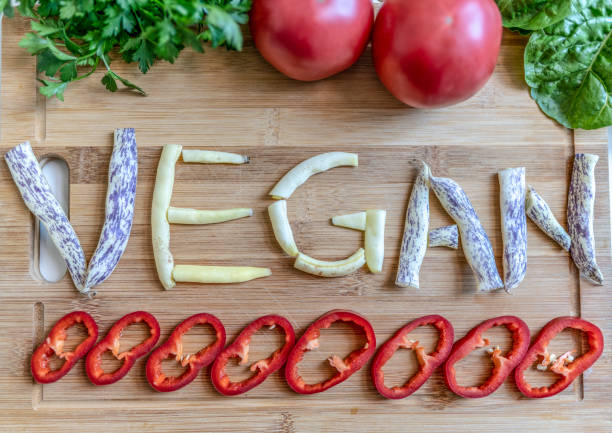 istock Vegan word written with variation of vegetables on cutting board 1296734457