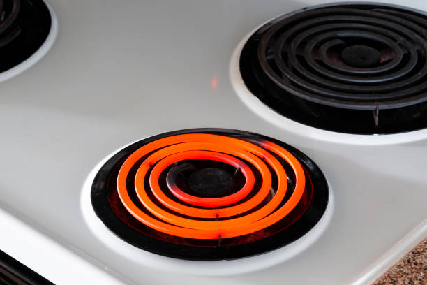 Hot Burner On Stove Top Horizontal shot of a white stove top with one hot burner and two off.  Shot at an angle. burner stove top photos stock pictures, royalty-free photos & images