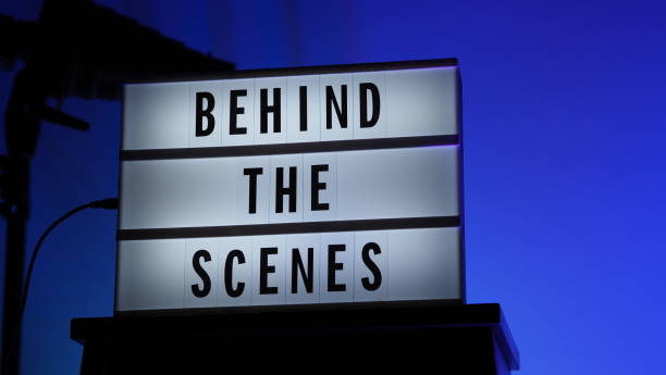 istock Cinema Light box. Behind the scenes letterboard text on Lightbox. Multi color LED on background. Sillhouette flash snoot hood on tripod. video production studio. Behind the scene Lightbox 1296735557
