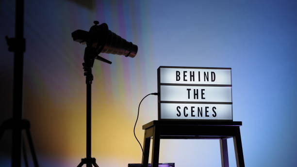 istock Cinema Light box. Behind the scenes letterboard text on Lightbox. Multi color LED on background. Sillhouette flash snoot hood on tripod. video production studio. Behind the scene Lightbox 1296735601