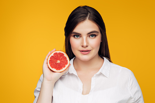 Portrait of a girl holding red grapefruit. Plus size model