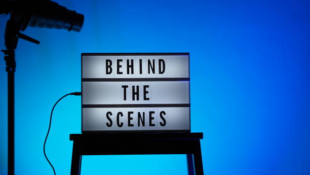 istock Cinema Light box. Behind the scenes letterboard text on Lightbox. Multi color LED on background. Sillhouette flash snoot hood on tripod. video production studio. Behind the scene Lightbox 1296736956