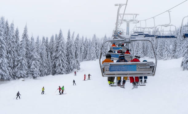 Skiers ride the cable car while other skiers ski down the mountain
