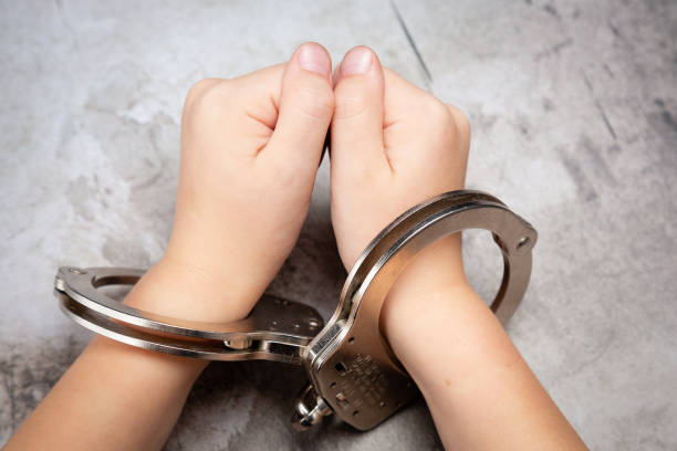White Young Child's Hands in Jail Handcuffs Picture of young child's hands in hand cuffs handcuffs stock pictures, royalty-free photos & images