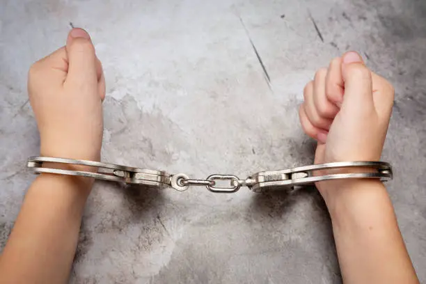 Photo of White Young Child's Hands in Jail Handcuffs