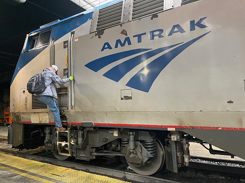 Engineer with Facemask Climbs Down Amtrak Locomotive at Platform in Washington DC