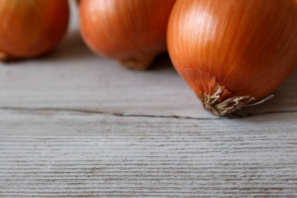istock onions in a wooden background 1296743643