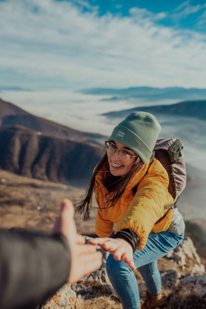 istock People helping each other hike up a mountain at sunrise. 1296743686
