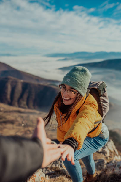 istock People helping each other hike up a mountain at sunrise. 1296743687