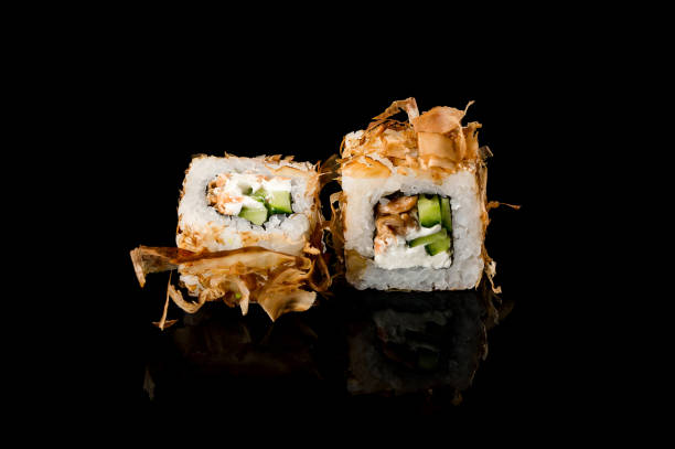 istock Two orange salmon rolls on a black background with reflection. Close-up, top view. Food delivery concept. 1296744772