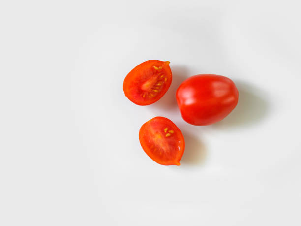 One Whole and Two Haves Red Grape Tomato on White Backgrounds Large cherry tomatoes for healthy food background image with copy space grape tomato stock pictures, royalty-free photos & images