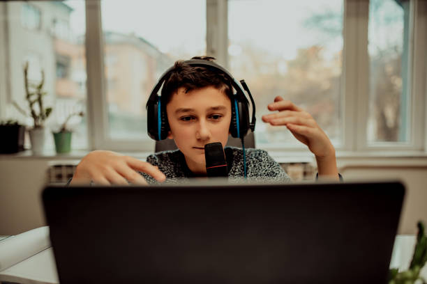 istock Boy attending online classes from home. Child using laptop and headsets for connecting with teacher and schoolmates. School education and social distance during quarantine 1296748992