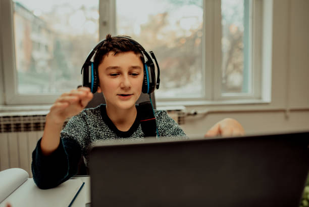 istock Boy attending online classes from home. Child using laptop and headsets for connecting with teacher and schoolmates. School education and social distance during quarantine 1296749010