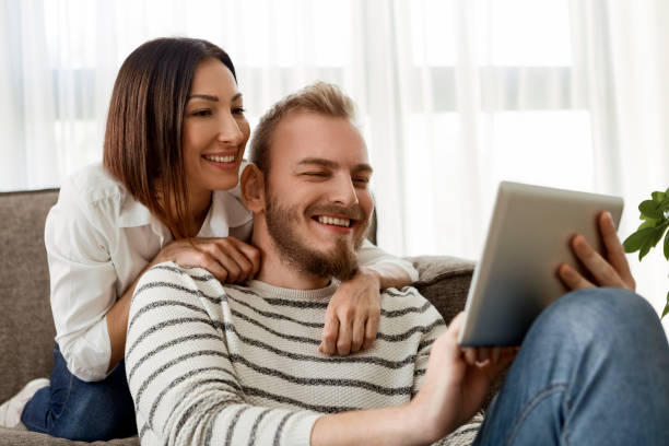 istock Girl Massaging Boyfriend On Sofa At Home looking at digital tablet 1296749849