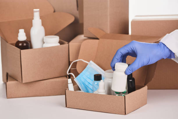 istock Hand in glove adding a bottle of pills into a cardboard parcel 1296751078
