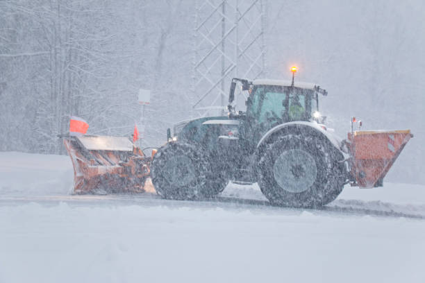 tracteur de chasse-neige avec gritter dégageant une route de campagne pendant un blizzard - spreader photos et images de collection