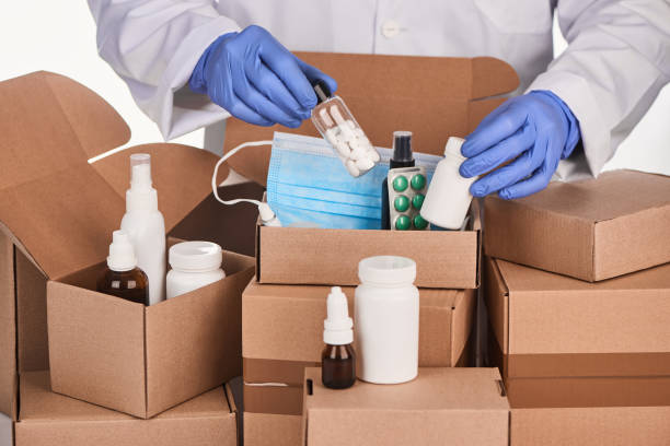 istock Pharmacist's hand putting a set of medications into cardboard boxes 1296751227