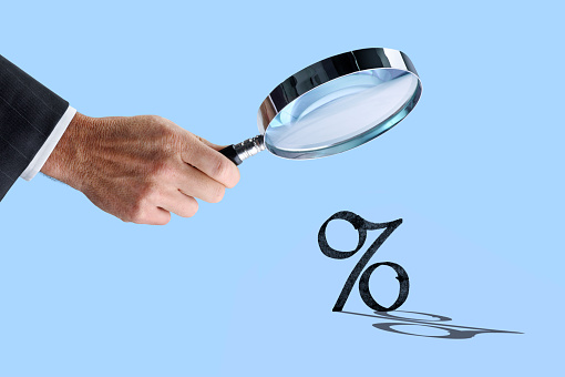Man Holding Magnifying Glass Looks At Interest Rates