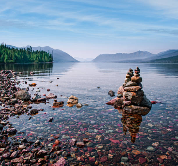 Rock Cairn at Lake McDonald Lake McDonald is 10 miles long and over a mile wide making it the largest lake in Glacier National Park. It fills a deep valley formed by erosion and glacial activity. Lake McDonald is on the west side of the Continental Divide. The Going-to-the-Sun Road parallels the lake along its southern shoreline. The lake was photographed from Lake McDonald Lodge in Glacier National Park, Montana, USA. jeff goulden mountain stock pictures, royalty-free photos & images