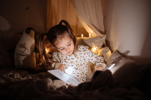 Shot of an adorable little girl reading a book in her bedroom at home