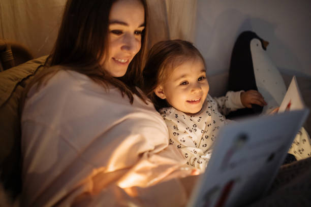 istock Mother and child reading book in bed before going to sleep 1296760408