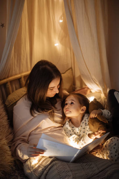 istock Mother and child reading book in bed before going to sleep 1296760429