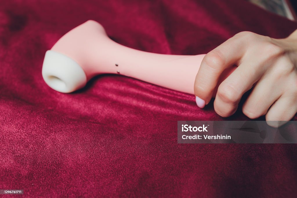 Woman in bedroom holding vibrator in hand. Woman in bedroom holding vibrator in hand Vibrator Stock Photo