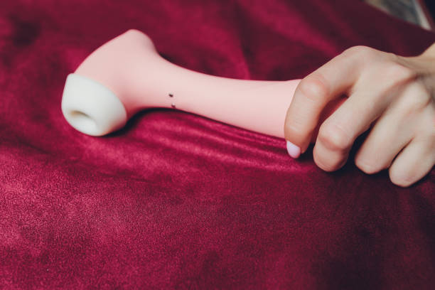 Woman in bedroom holding vibrator in hand. stock photo
