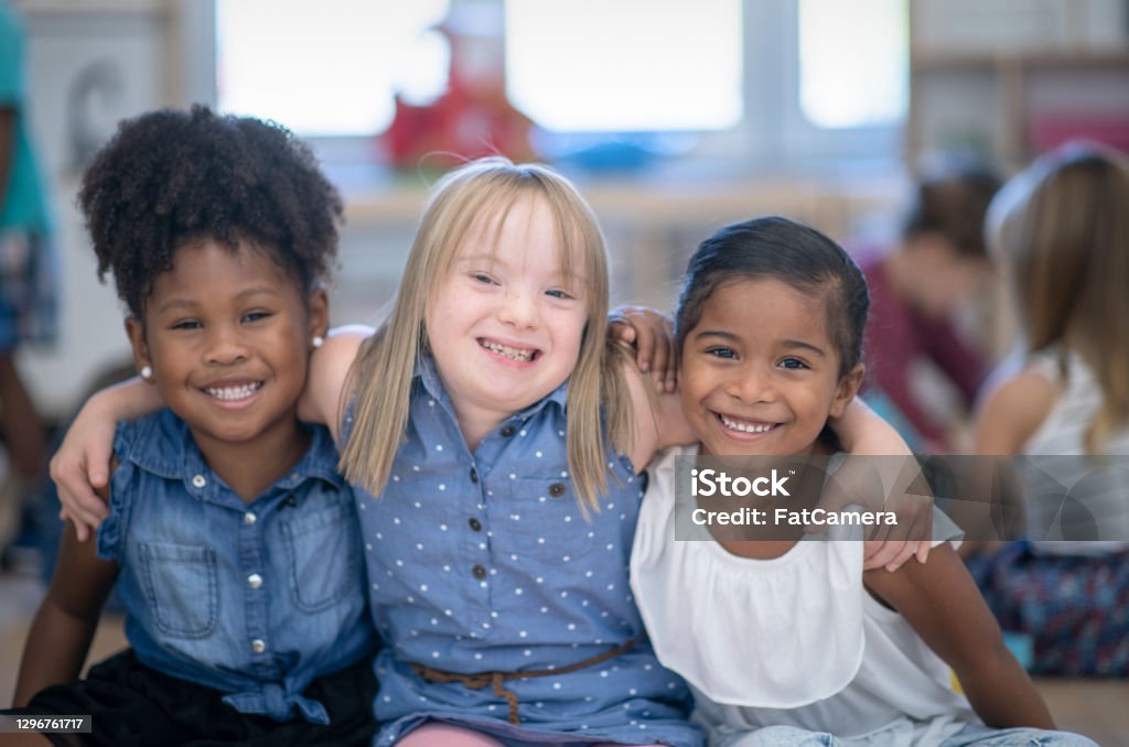 Best friends in preschool Three multi ethnic preschool girls in their classroom. One of the girls (in the middle) is of Caucasian ethnicity and has Down syndrome. The other girls are of African and mixed race ethnicity. Child Stock Photo