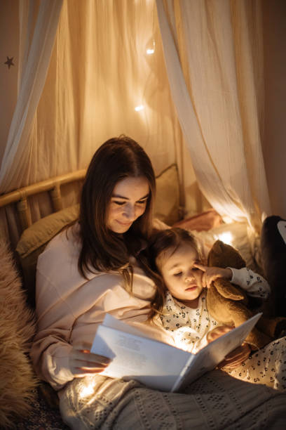 istock Mother and child reading book in bed before going to sleep 1296762178