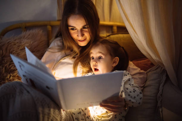 istock Mother and child reading book in bed before going to sleep 1296762264