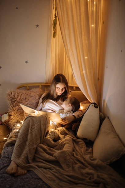 istock Mother and child reading book in bed before going to sleep 1296762371