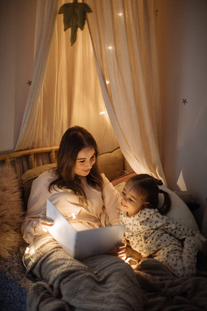 istock Mother and child reading book in bed before going to sleep 1296762909