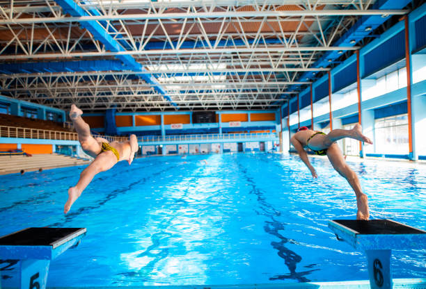 istock Two swimmers jumping into pool from starting swimming position 1296767209