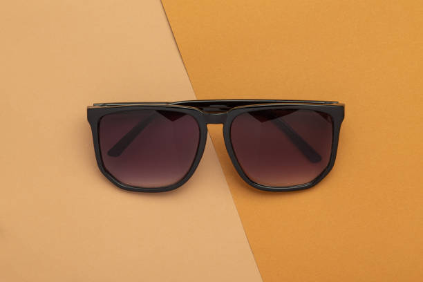 istock Brown sunglasses isolated on beige half brown background 1296775989