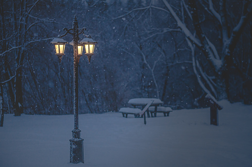 The light and heat from the street lamp melt the snow, which when it falls freezes due to the low temperatures