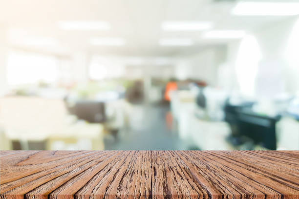 istock abstract blur inside office with modern wood table perspective for show ads or promote product and content on display concept 1296782541