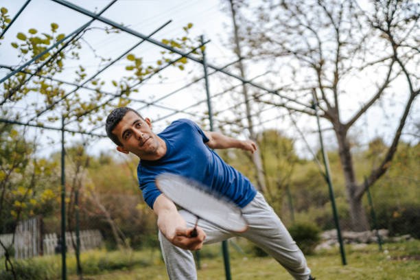 istock Young man playing badminton in backyard 1296785830