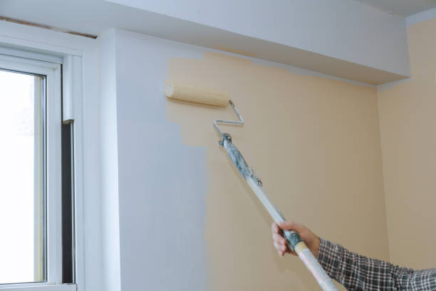 istock Rear view of painter paints the wall with a roller 1296787433